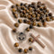 A rosary with tiger's eye beads, a round silver medal with St Charbel portrait, and a polished silver cross.