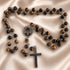 A Catholic rosary with tiger's eye beads, a round metal centerpiece, and a matte cross, on a beige satin fabric.