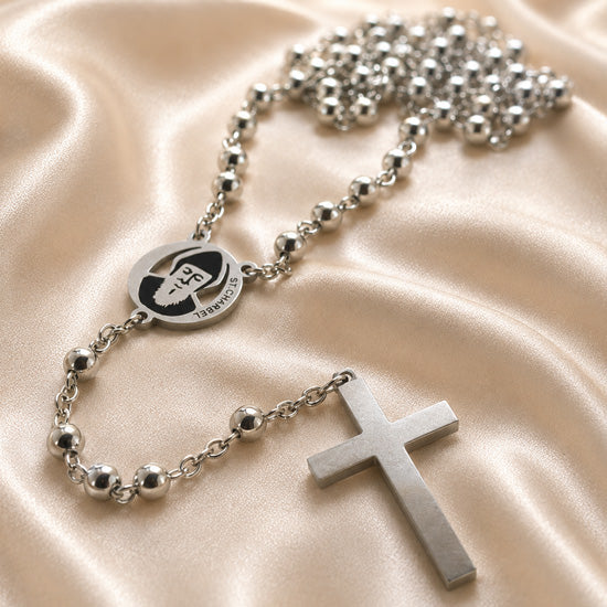 Stainless steel rosary close-up with circular St. Charbel medal, cross pendant, and beads.