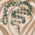 A rosary with green and white marbled beads, silver-tone chain links, a round medallion and a crucifix.