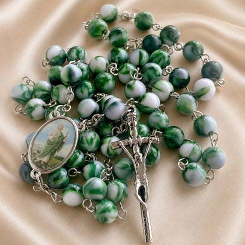A green and white marbled bead rosary with a silver crucifix and an oval medallion.