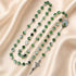 A green and white marbled beaded rosary with a silver crucifix and centerpiece medallion.