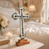 Budded cross on a night table next to a bad in white ambient