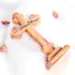 Image of a back of an hand-crafted small standing olive wood cross with petals around it, against white background.