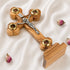 A hand-crafted small standing olive wood crucifix with halo and intricate details, featuring olive leaves, dried flowers, holy soil and incense.
