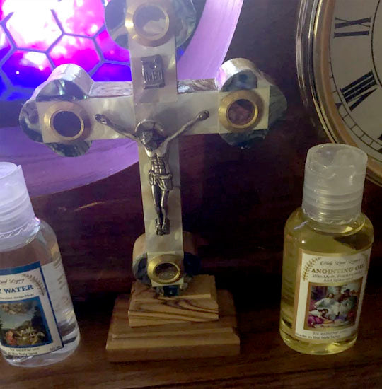 Budded olive wood cross with Mother of Pearl and crucifix standing next to Holy Water vial.