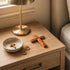 Wooden nightstand with jewelry, a cross, and a lamp.