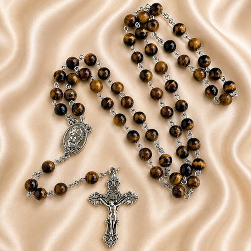 A Catholic rosary with brown tiger's eye beads, a silver-tone crucifix, and an oval centerpiece medal.
