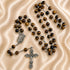 A Catholic rosary with brown tiger's eye beads, a silver-tone crucifix, and an oval centerpiece medal.