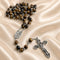 A Catholic rosary with brown and black tiger's eye beads, a silver-tone medal, and an ornate silver crucifix.