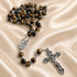 A Catholic rosary with brown and black tiger's eye beads, a silver-tone medal, and an ornate silver crucifix.