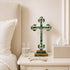 Decorative cross on a nightstand next to a glass of water and a box of tissues.