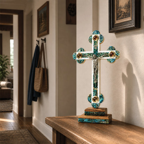 Decorative cross with turquoise and gold accents on a wooden surface in a home setting.