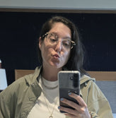 Woman with glasses and a phone in front of the mirror