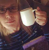 Woman with glasses showing a white cup.