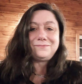 Middle aged woman in wooden cabin smiling at the camera