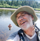 Older man with a hat taking a selfie in nature