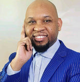 Middle aged African bold man with beard and blue suit.