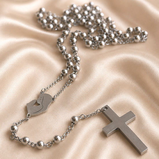 Close-up of stainless steel rosary chain with round beads, Virgin Mary charm, and cross