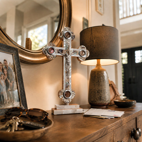 Budded white altar crucifix on home entrance next to a lamp and a mirror