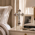 Decorative cross on a nightstand with books and a lamp in a bedroom setting
