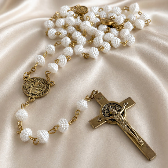White rosary with textured beads, gold crucifix, and round St. Benedict medal charm