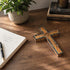 Wooden latin cross on a table next to a notebook and a plant