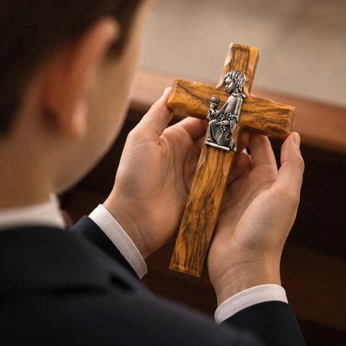 Boy holding a wooden communion cross in his hands