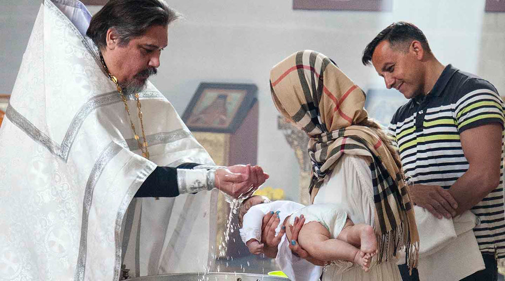 A priest baptising a baby held by the parents