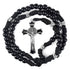 Men's rosary with black acrylic and silver Our Father beads, black crucifix and strong black cord, laid on white background.