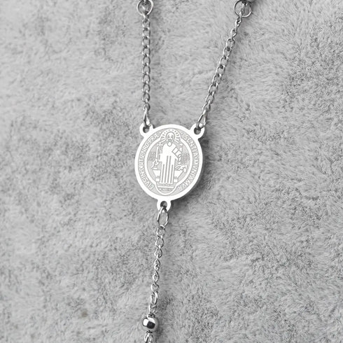 Silver Saint Benedict rosary with 4mm stainless steel beads and cross, laid on grey background.