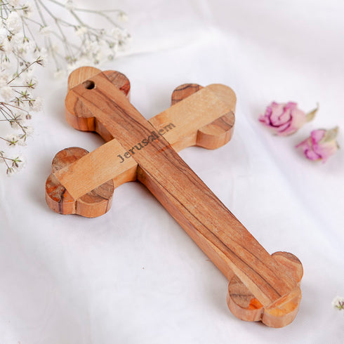 Back of an olive wood budded cross from Bethlehem with word "Jerusalem" , laid on white surface with rose petals.