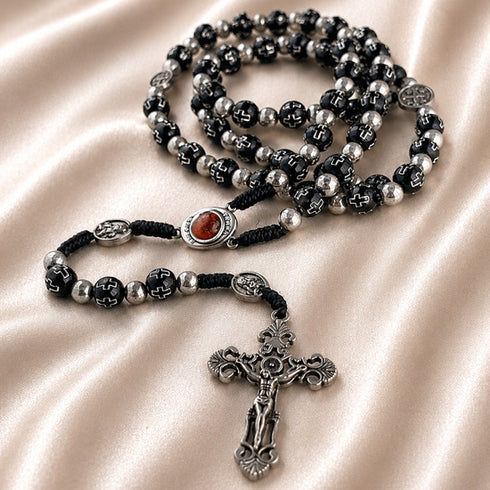 Black bead rosary with silver accents, Holy Soil centerpiece, and ornate silver crucifix on a satin cloth