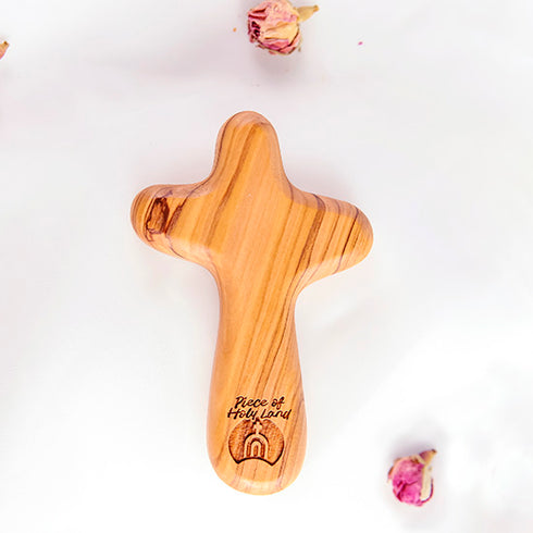 Olive wood comfort cross with the Piece of Holy Land logo, shown on white background with roses