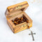 Open medium size olive wood box with an olive wood oval bead rosary in it with a silver cross poking out from the box