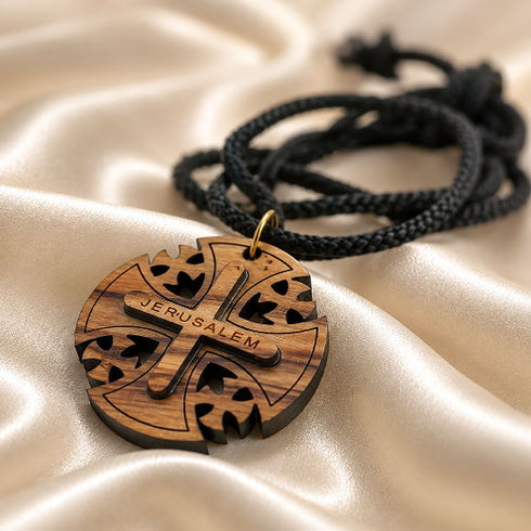 Round wooden Jerusalem cross pendant on black cord, shown from side angle