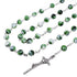 Green and white rosary with a silver cross on a white background