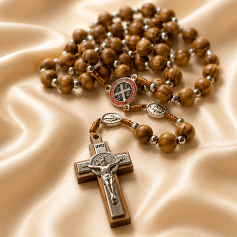 Olive wood prayer beads with St. Benedict medal centerpiece and silver crucifix on satin cloth.