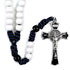 Rosary with white beads, blue and black beaded strands, and a silver cross on a white background.